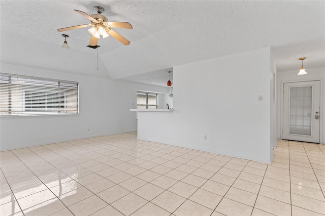 tiled empty room featuring ceiling fan, vaulted ceiling, and a textured ceiling