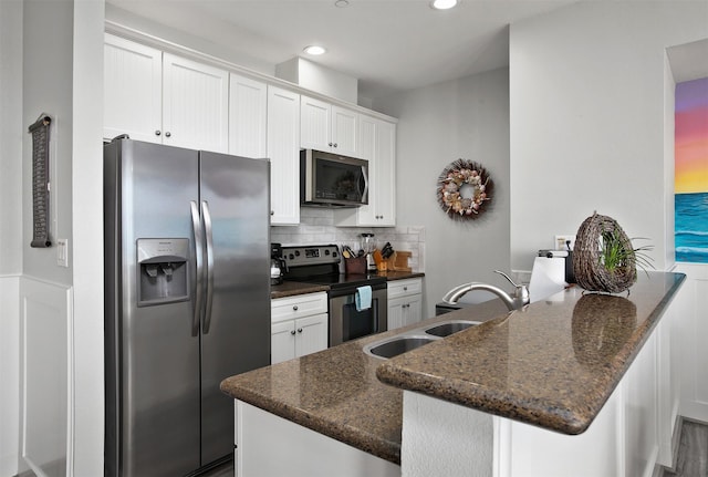 kitchen with stainless steel appliances, white cabinets, and dark stone counters