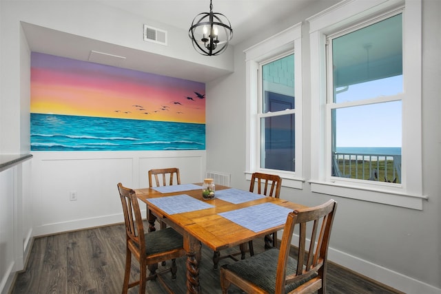 dining area featuring a water view, an inviting chandelier, and dark hardwood / wood-style flooring