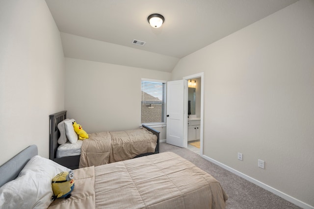 bedroom featuring ensuite bath, vaulted ceiling, and light carpet