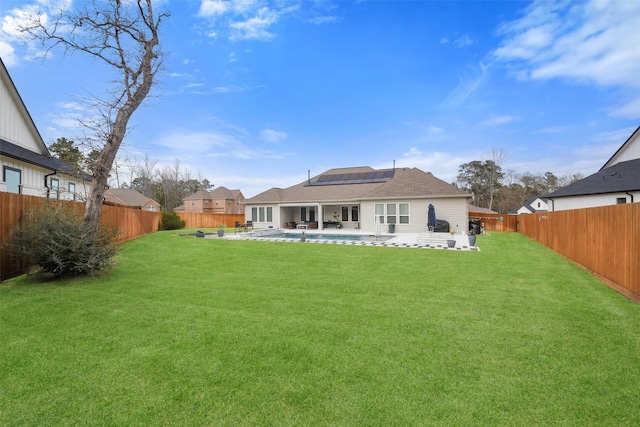 rear view of house with a patio, a lawn, and solar panels