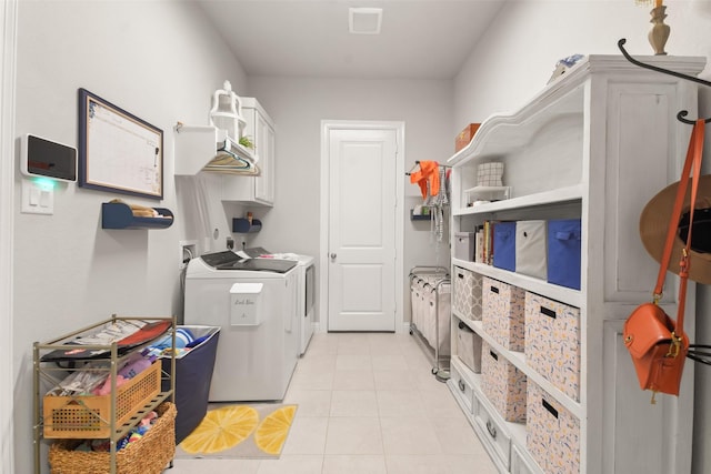 washroom with cabinets, washer and clothes dryer, and light tile patterned floors