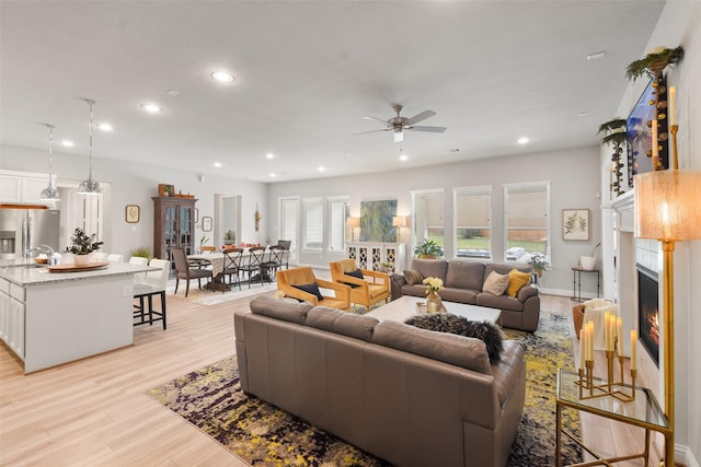 living room with light hardwood / wood-style flooring, ceiling fan, and sink