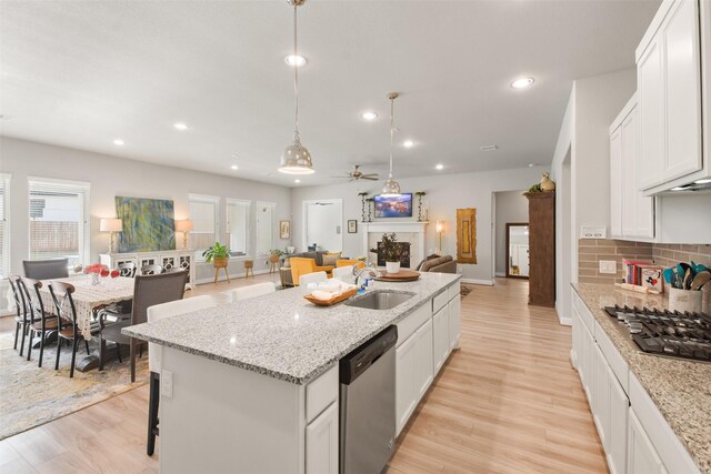 kitchen featuring stainless steel appliances, white cabinets, pendant lighting, sink, and a kitchen island with sink