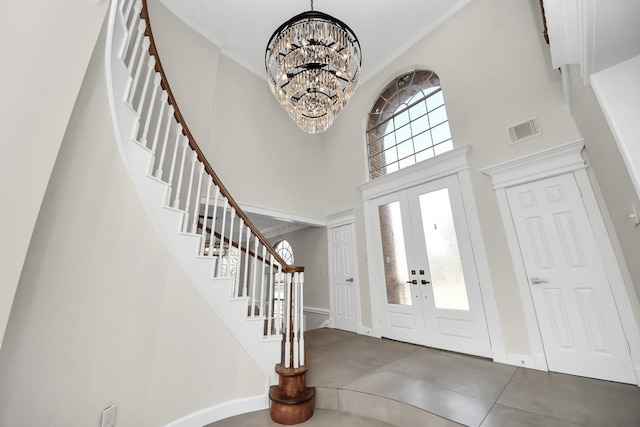 foyer featuring an inviting chandelier, french doors, a towering ceiling, and a healthy amount of sunlight