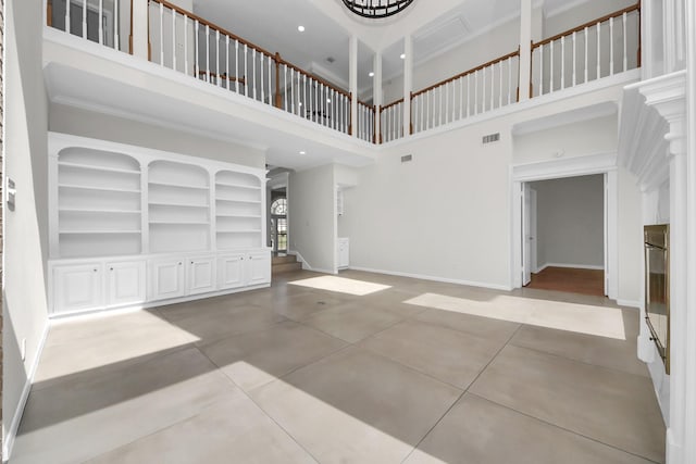 unfurnished living room featuring a high ceiling, ornamental molding, and ornate columns