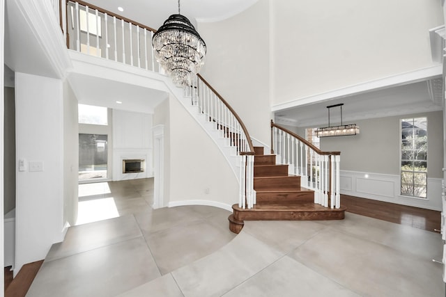 entryway with ornamental molding, a towering ceiling, and a chandelier