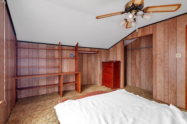 unfurnished bedroom with lofted ceiling, ceiling fan, and wood walls