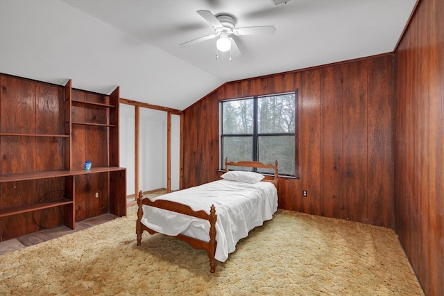 bedroom with carpet flooring, wooden walls, ceiling fan, and vaulted ceiling