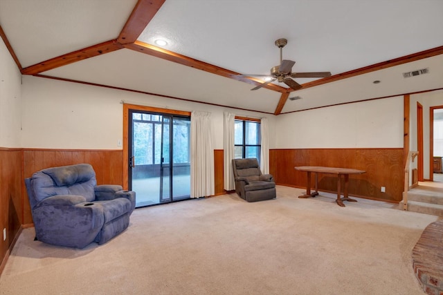 living area with light colored carpet, wooden walls, lofted ceiling with beams, and ceiling fan