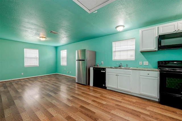 kitchen featuring sink, white cabinetry, a textured ceiling, light wood-type flooring, and black appliances