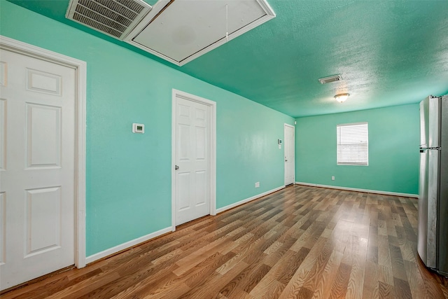 spare room with hardwood / wood-style floors and a textured ceiling