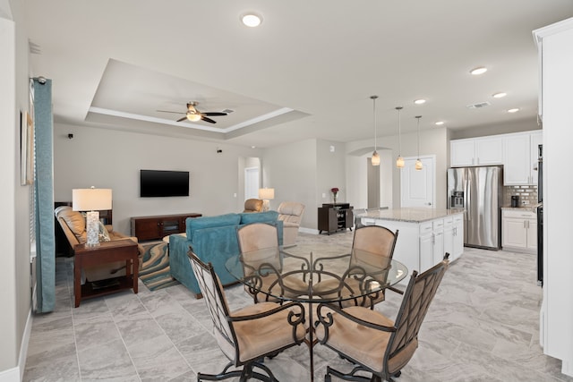 dining room featuring ceiling fan and a raised ceiling