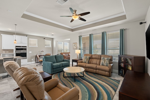 living room featuring crown molding, ceiling fan, and a tray ceiling