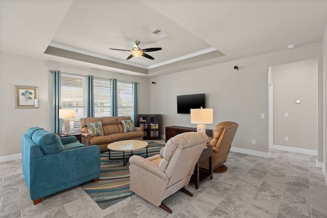 living room with ceiling fan and a raised ceiling