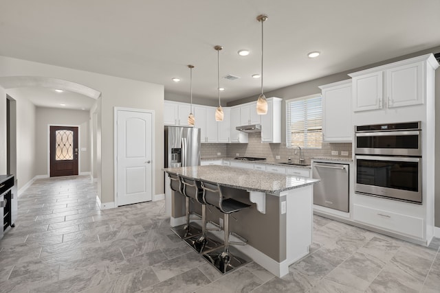 kitchen featuring a kitchen island, sink, white cabinets, light stone counters, and stainless steel appliances