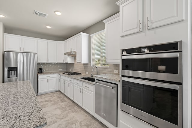 kitchen featuring stainless steel appliances, light stone countertops, and white cabinets