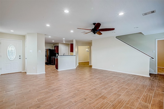 unfurnished living room featuring ceiling fan and light wood-type flooring