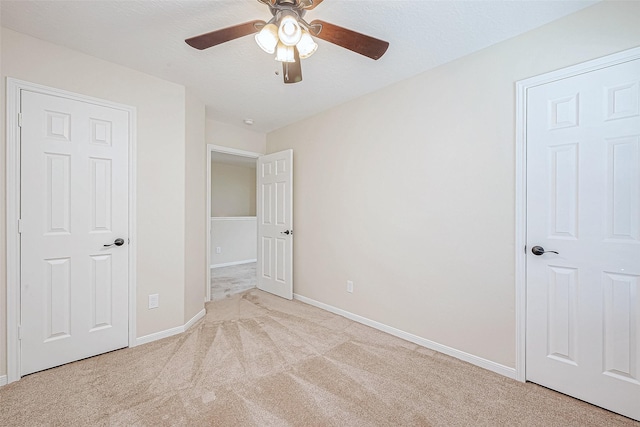 unfurnished bedroom with ceiling fan, light carpet, and a textured ceiling