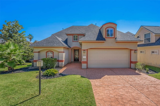 french country inspired facade with a front yard, roof with shingles, stucco siding, a garage, and driveway