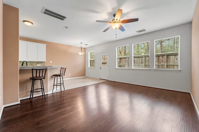 unfurnished living room with dark hardwood / wood-style flooring, sink, and ceiling fan