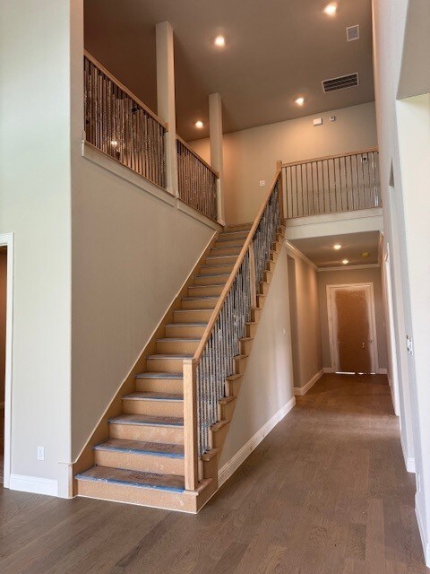 16147 Rustling Woods Rd, Conroe, TX 77302 - stairs with wood finished floors, baseboards, a high ceiling, and recessed lighting