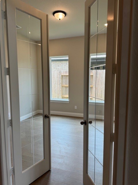 16147 Rustling Woods Rd, Conroe, TX 77302 - corridor with french doors, baseboards, and wood finished floors