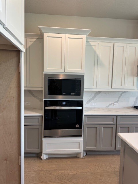 16147 Rustling Woods Rd, Conroe, TX 77302 - kitchen with stainless steel appliances, gray cabinets, light countertops, and light wood finished floors