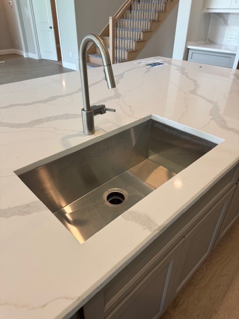 16147 Rustling Woods Rd, Conroe, TX 77302 - kitchen view of a sink, light stone counters, and baseboards