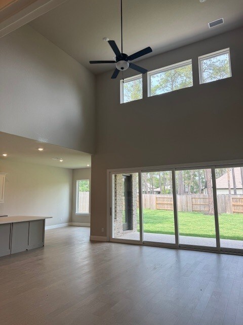 16147 Rustling Woods Rd, Conroe, TX 77302 - unfurnished living room featuring high vaulted ceiling, light wood-style flooring, baseboards, ceiling fan, and recessed lighting