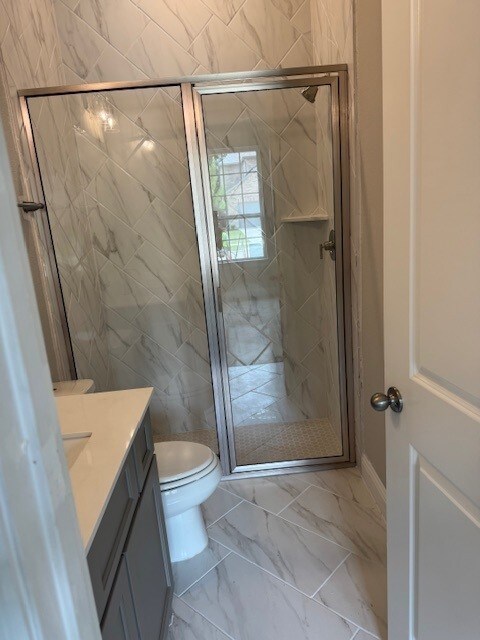 16147 Rustling Woods Rd, Conroe, TX 77302 - full bathroom with marble finish flooring, a stall shower, vanity, and toilet