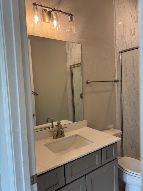 16147 Rustling Woods Rd, Conroe, TX 77302 - bathroom with vanity, toilet, and a tile shower
