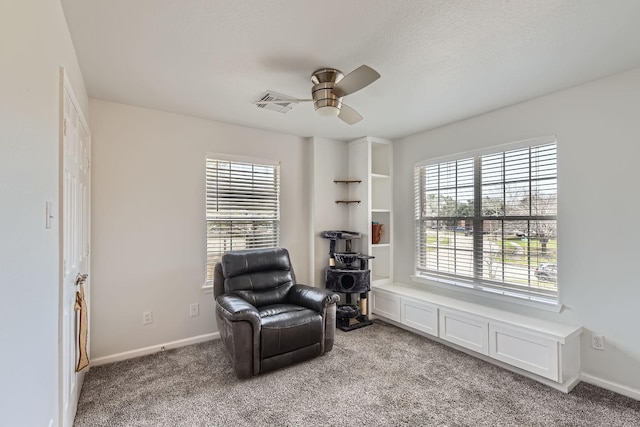 living area featuring carpet, ceiling fan, and a textured ceiling