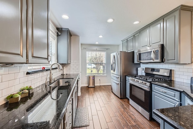 kitchen featuring appliances with stainless steel finishes, sink, dark stone counters, and gray cabinetry