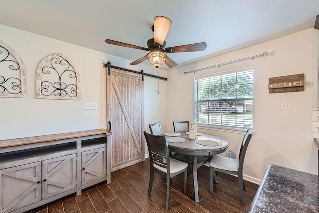 dining space featuring dark wood-type flooring, ceiling fan, and a barn door