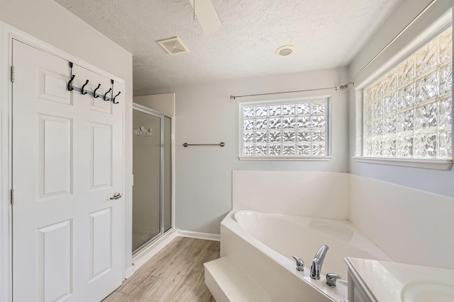 bathroom with plenty of natural light, independent shower and bath, a textured ceiling, and hardwood / wood-style floors