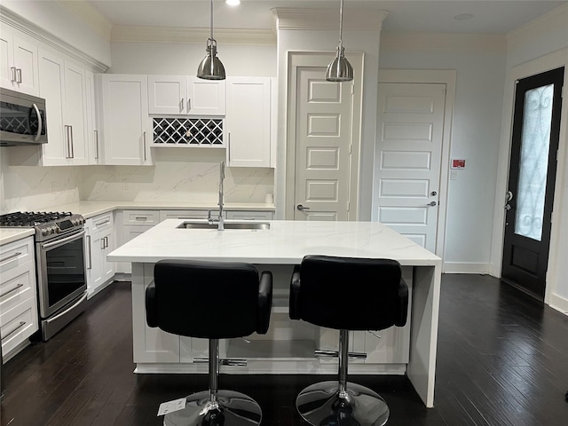 kitchen featuring decorative light fixtures, an island with sink, sink, white cabinets, and stainless steel appliances