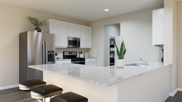 kitchen with sink, appliances with stainless steel finishes, light stone countertops, white cabinets, and kitchen peninsula