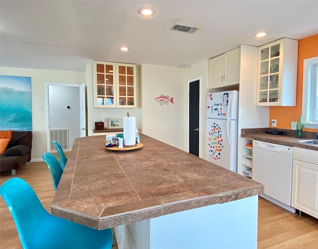 kitchen featuring white appliances, white cabinets, a kitchen breakfast bar, and light hardwood / wood-style floors