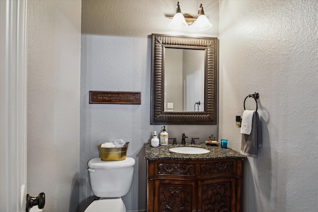 bathroom featuring a textured wall, vanity, and toilet