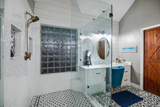 bathroom featuring lofted ceiling, a shower stall, vanity, and tile patterned floors