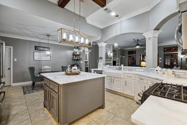 kitchen featuring arched walkways, ceiling fan, a sink, visible vents, and ornate columns