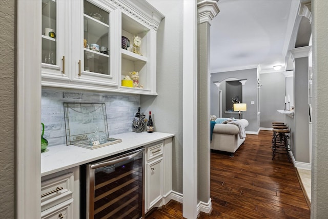 bar featuring a dry bar, wine cooler, ornamental molding, dark wood-style flooring, and backsplash