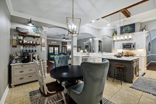 dining room featuring a ceiling fan, arched walkways, crown molding, and baseboards