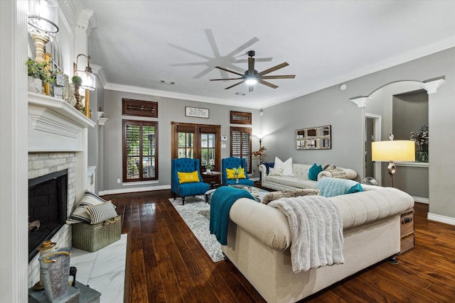 living area featuring a brick fireplace, crown molding, baseboards, and wood finished floors