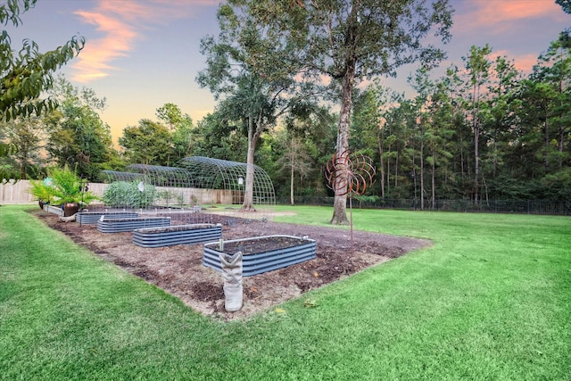 yard at dusk featuring a garden and fence