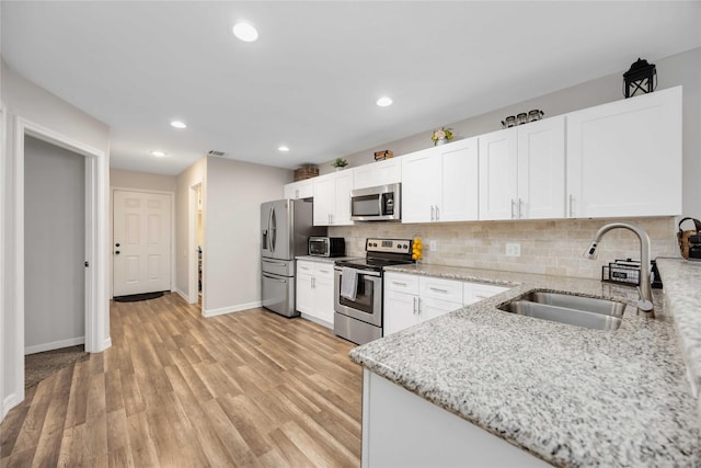 kitchen featuring white cabinetry, light hardwood / wood-style flooring, sink, light stone counters, and appliances with stainless steel finishes