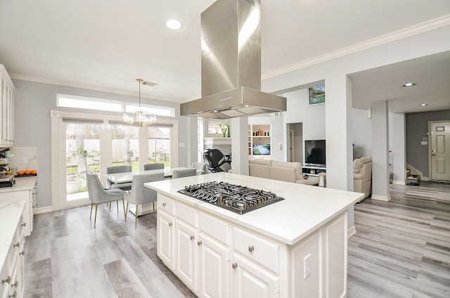 kitchen with white cabinetry, island exhaust hood, stainless steel gas stovetop, and a kitchen island