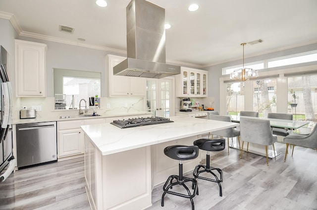 kitchen with a kitchen island, white cabinetry, appliances with stainless steel finishes, and island range hood