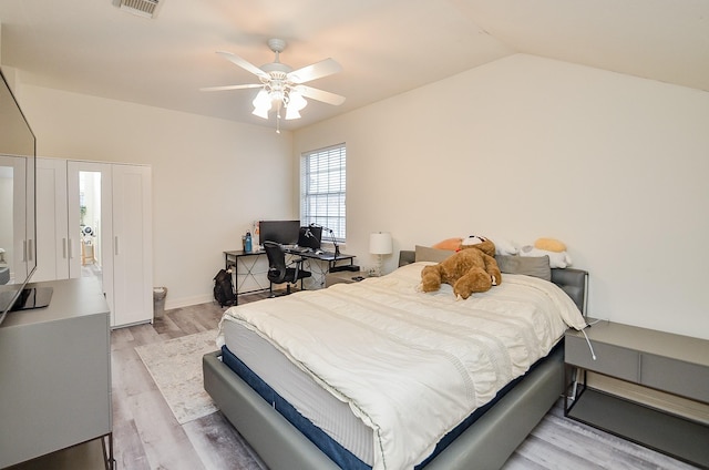 bedroom with ceiling fan, vaulted ceiling, and light wood-type flooring